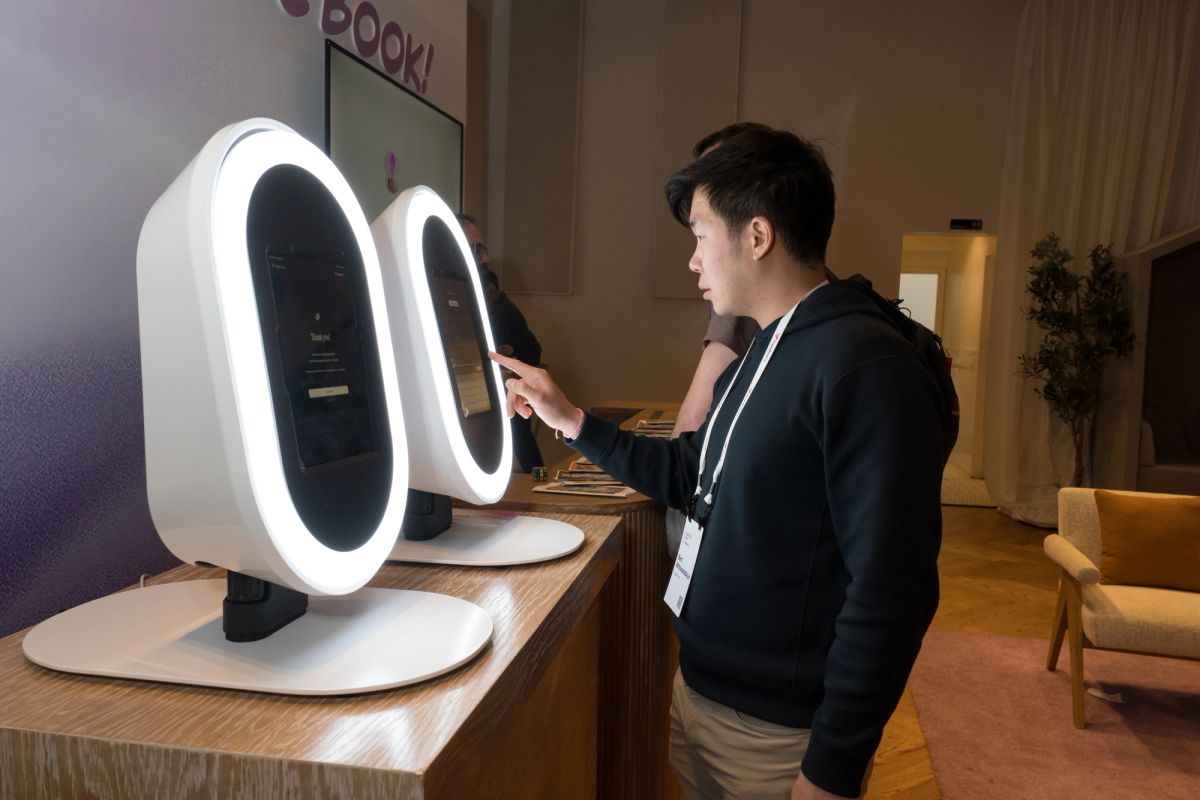 Man in dark sweater interacting with white oval-shaped tech display devices on wooden counter in modern.