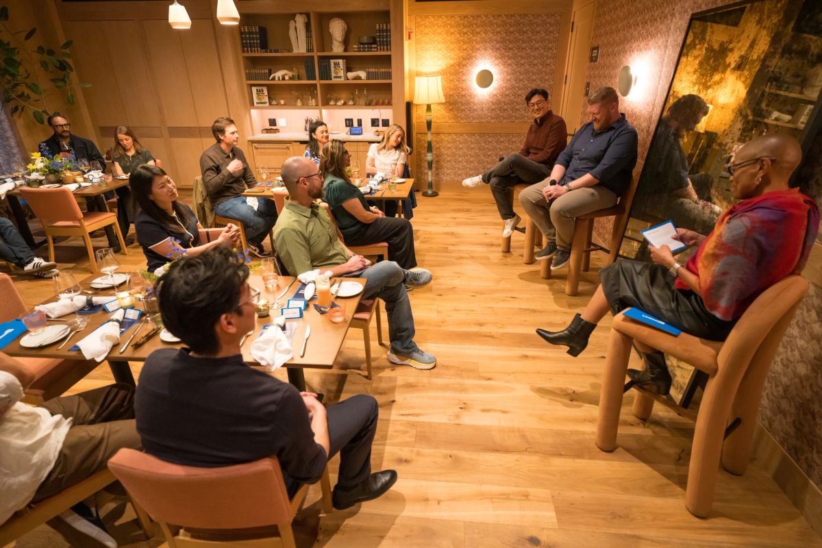 People sitting in chairs arranged in a circle during a panel discussion in a modern room with wood floors and.