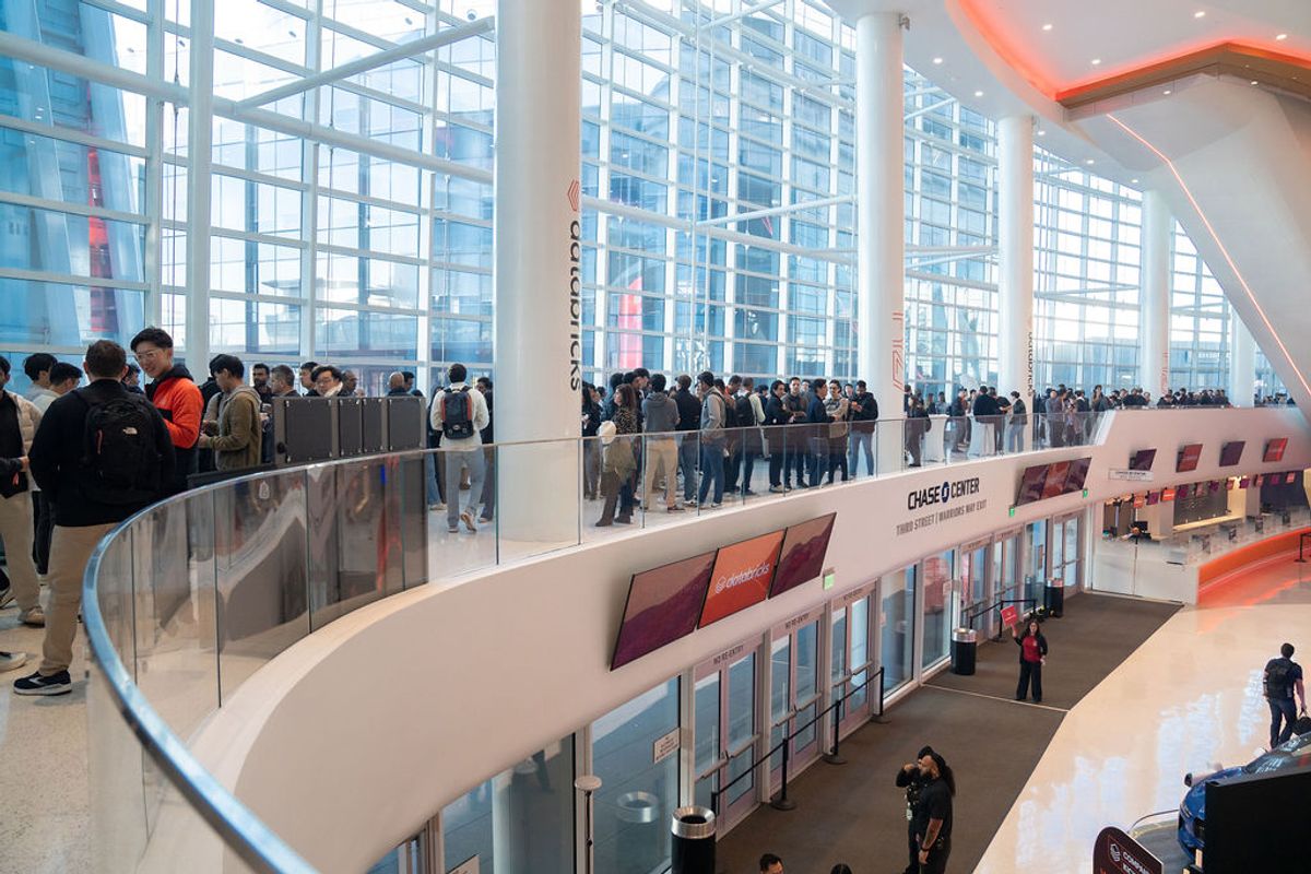 Conference attendees gather on curved balcony overlooking modern glass-walled venue with multiple levels