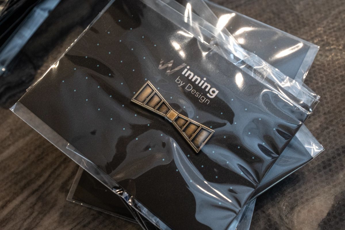 Black gift bags with silver ribbons containing conference swag items on a wooden surface