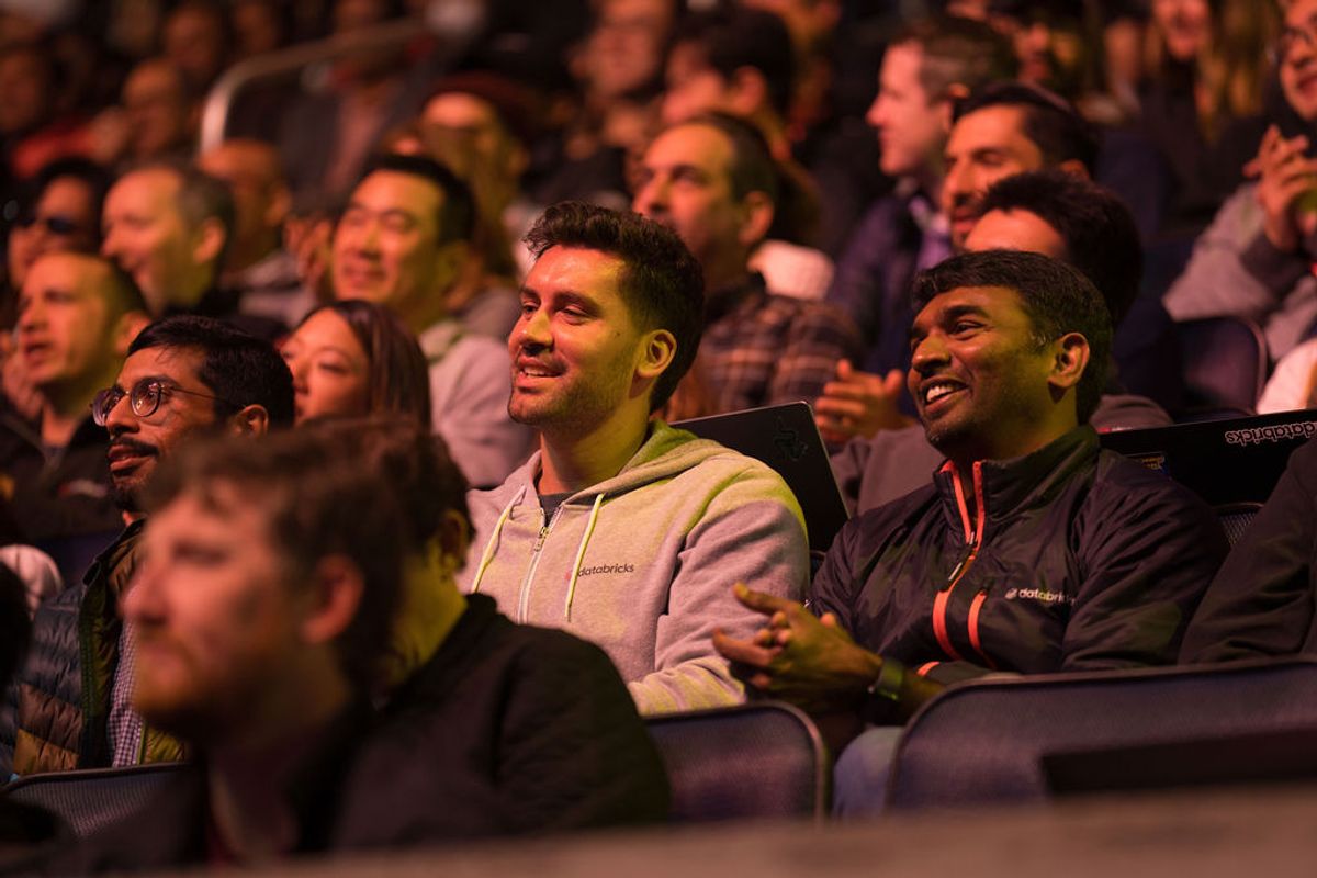 Audience members laughing and smiling while seated in auditorium chairs during a presentation or event