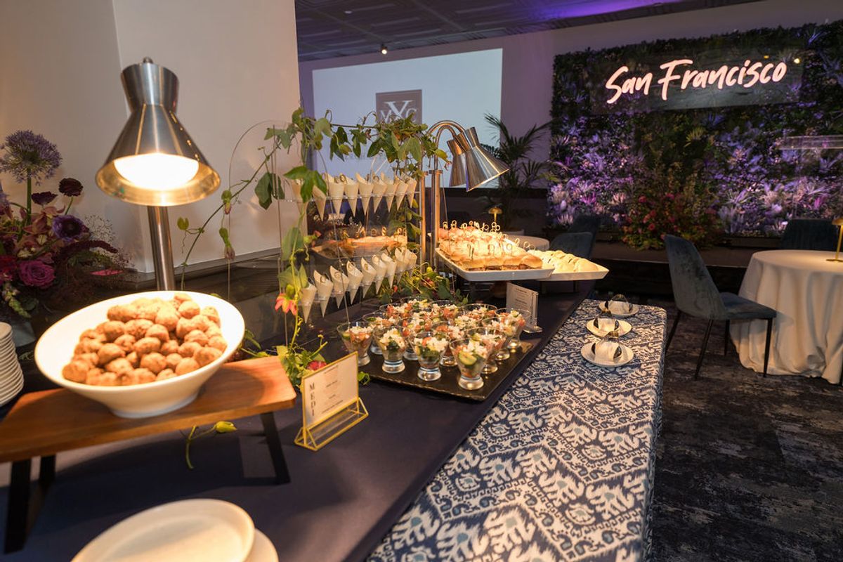 Buffet table with appetizers and warming lamps at networking reception, with San Francisco sign visible