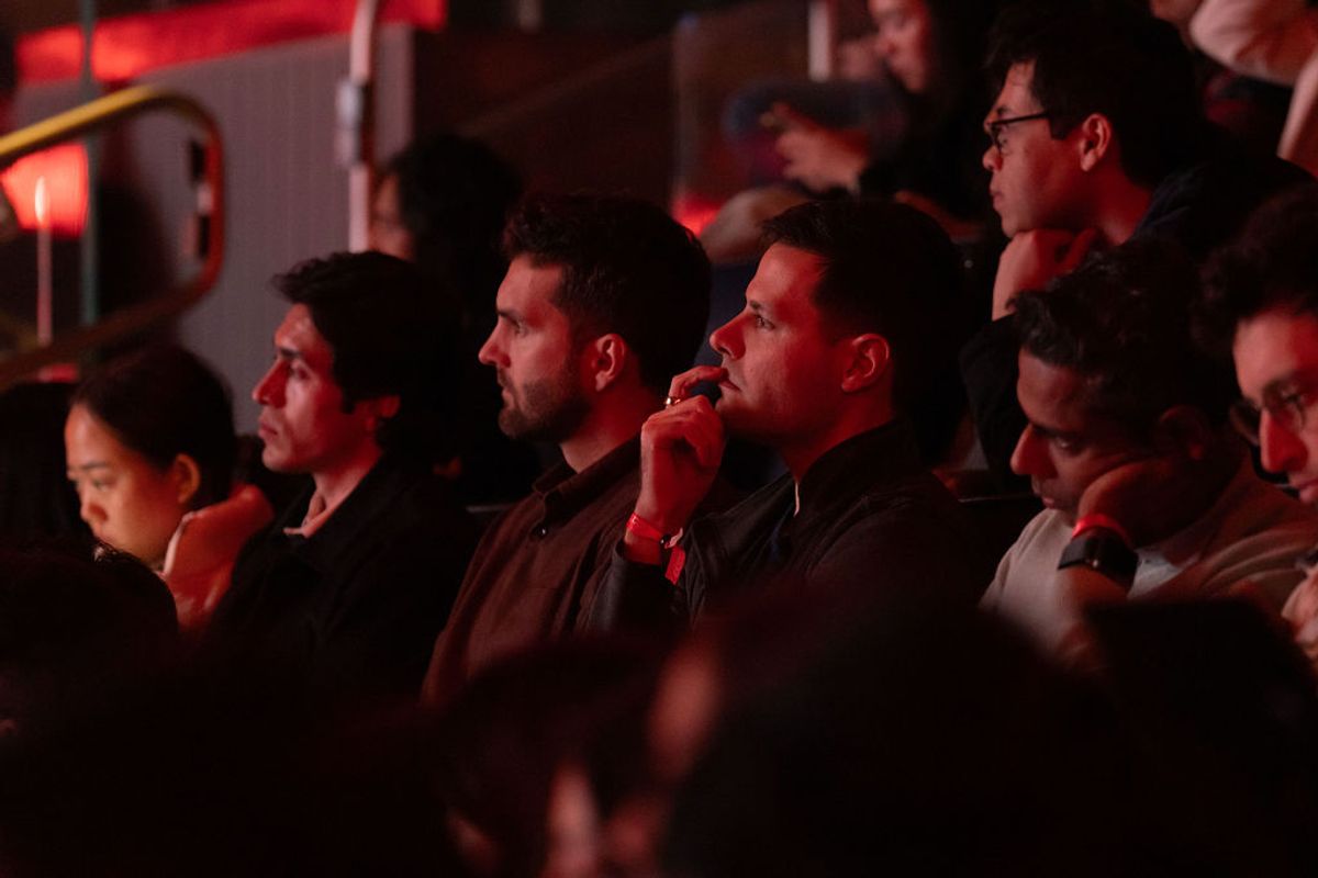 Attendees watching intently at a conference venue with red ambient lighting