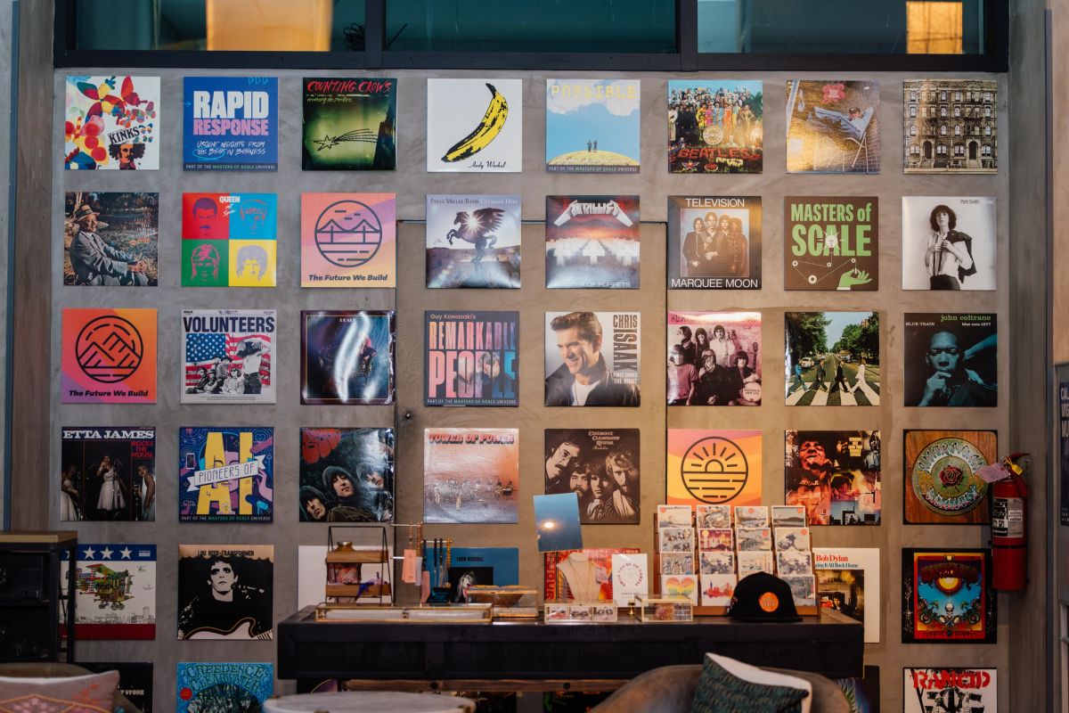 Wall display of vinyl album covers in a room with turntable and audio equipment below