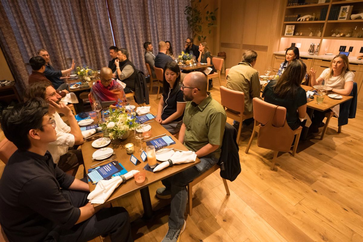 Business professionals seated around conference tables during a panel discussion in a modern meeting room