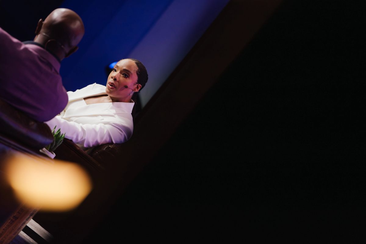 Two speakers on stage at a conference venue with dramatic lighting and stage setup
