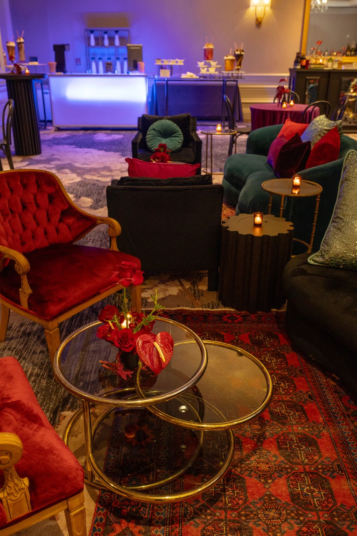 Elegant hotel lounge with red velvet chairs, dark sofas, gold coffee tables, and purple ambient lighting