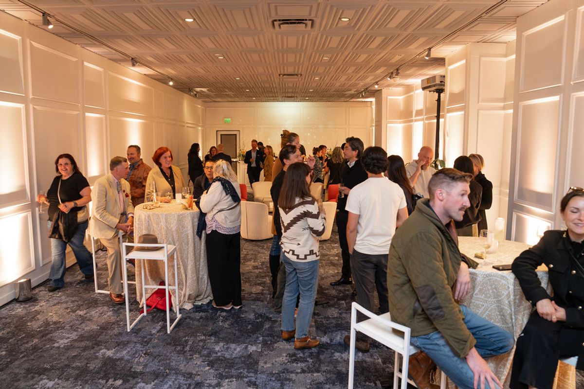 Attendees networking and socializing at a reception in an elegant event room with white cocktail tables