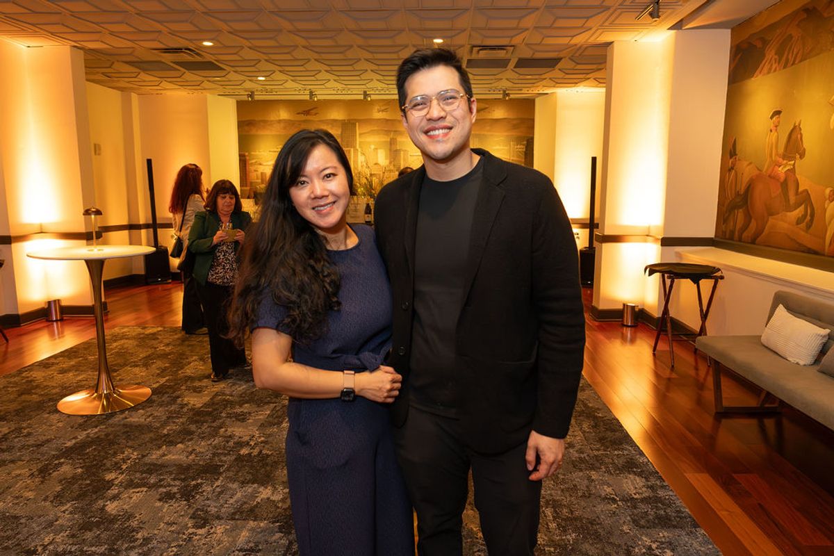 Two attendees pose together at a networking reception in an upscale venue with warm lighting and artwork.