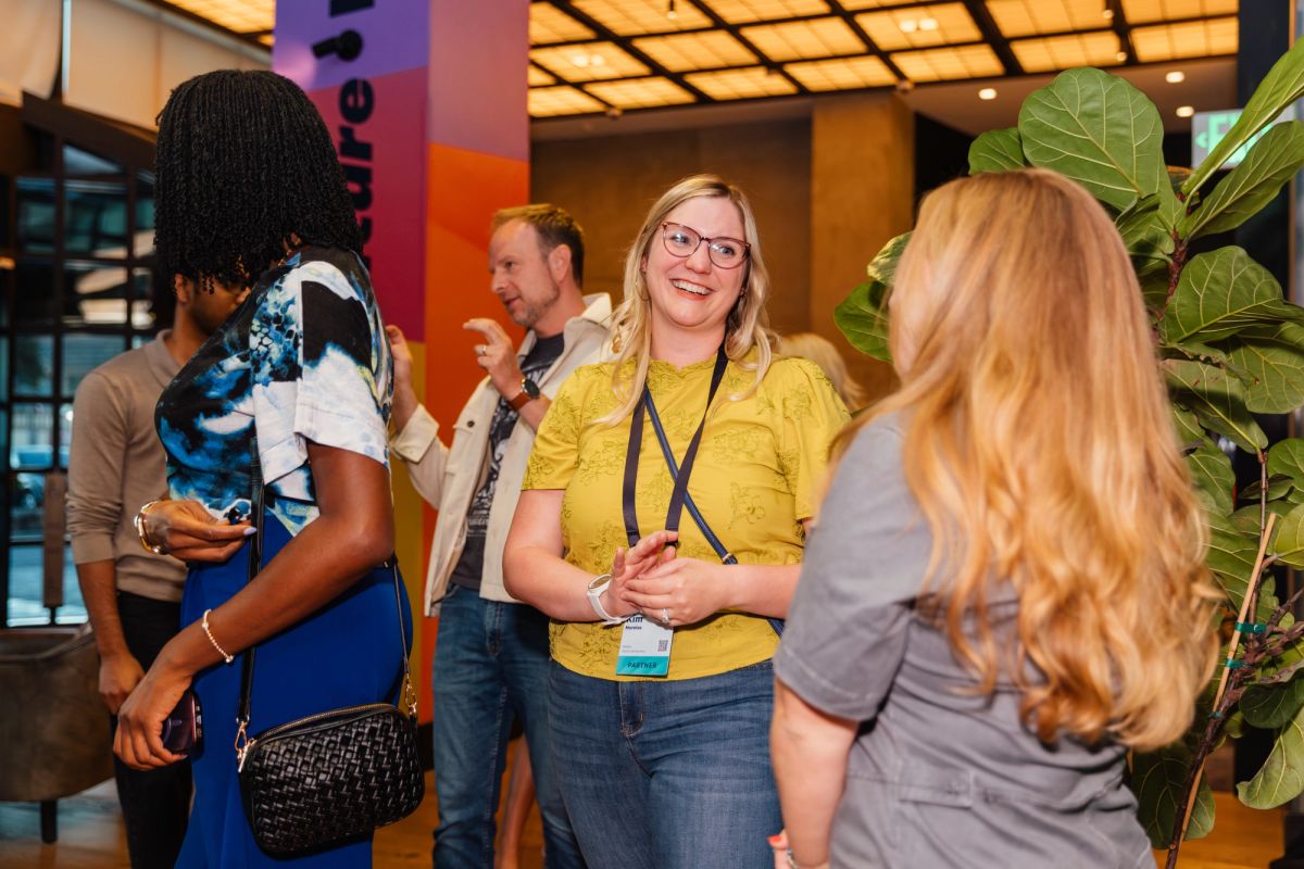 Conference attendees networking in modern lobby with colorful wall graphics and large plants