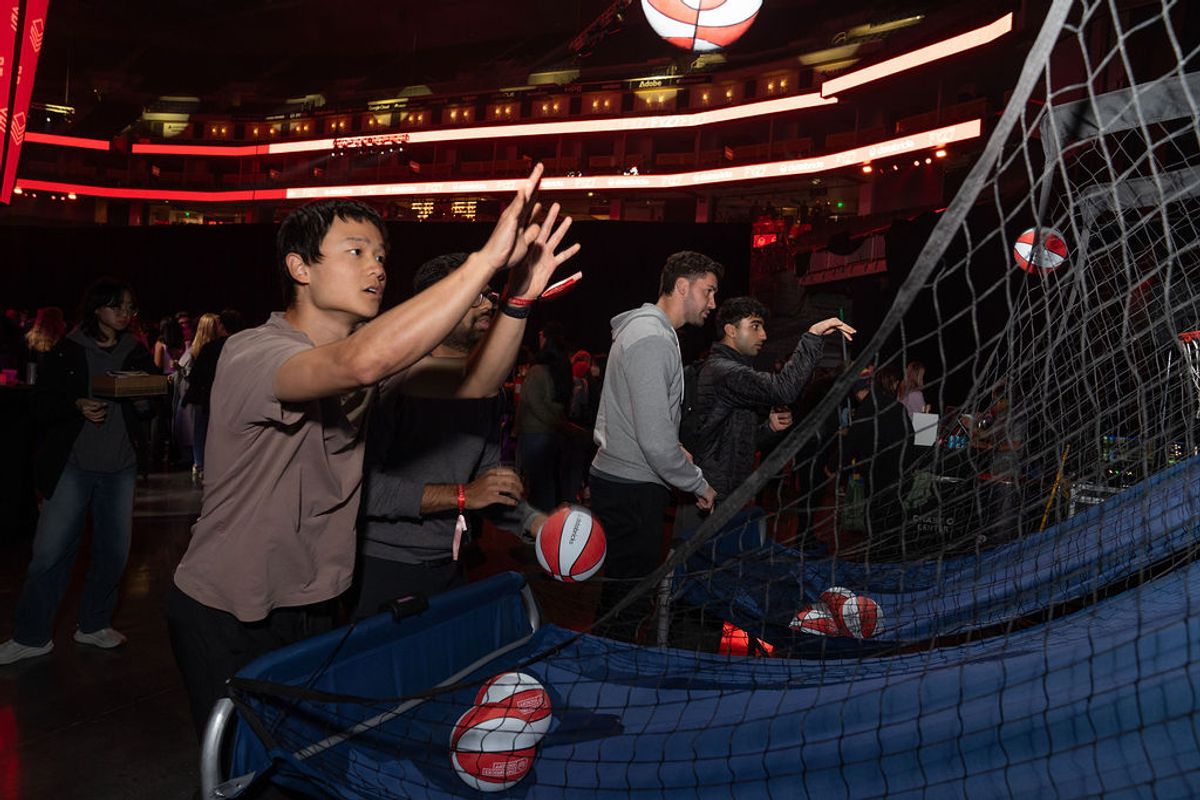 Attendees play an interactive game with red and white balls at an indoor venue with neon lighting.