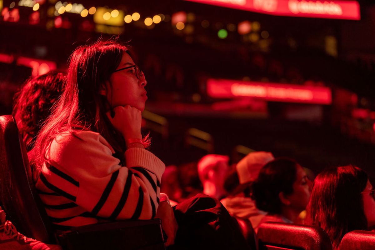 Attendee listening attentively in red-lit venue with blurred lights and audience members in background