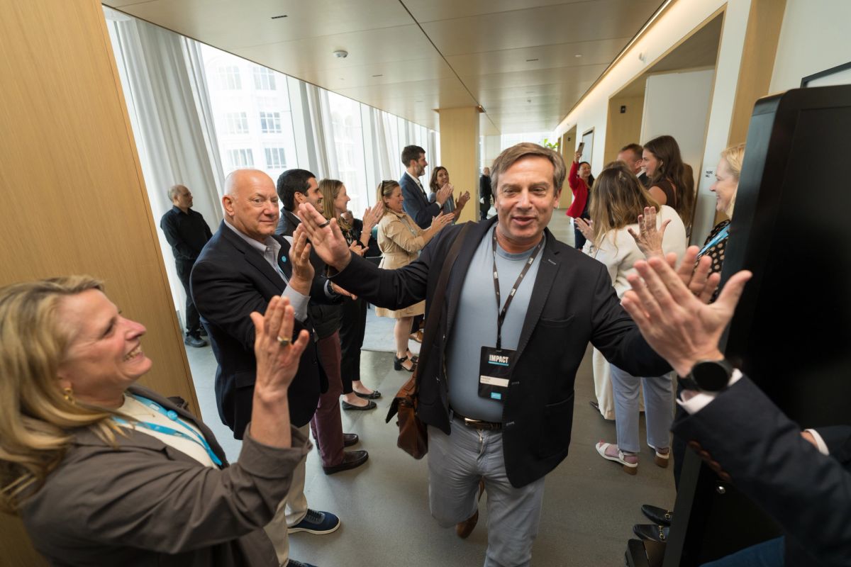 Business professionals high-fiving and celebrating in a modern conference venue with floor-to-ceiling windows