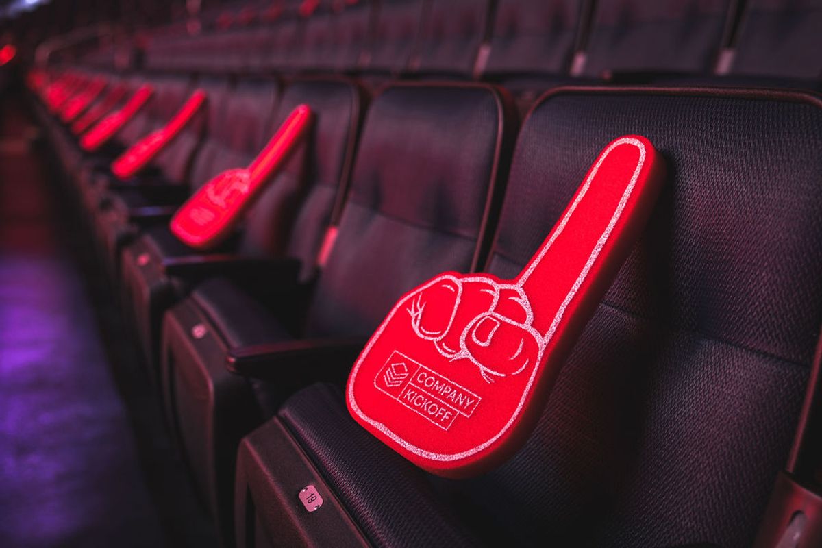 Red foam finger sits on dark stadium seat with red lighting illuminating the venue