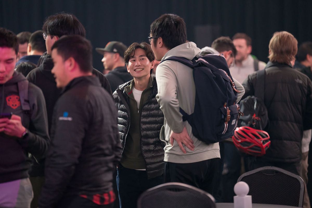 Attendees networking and socializing at an indoor conference event, with people standing and talking in small.