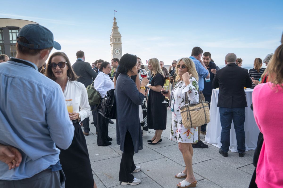 Business professionals networking at an outdoor rooftop event with city skyline and clock tower in background