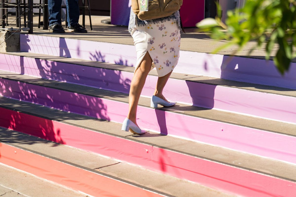 Person in floral skirt walking up colorful rainbow-painted concrete steps at outdoor venue