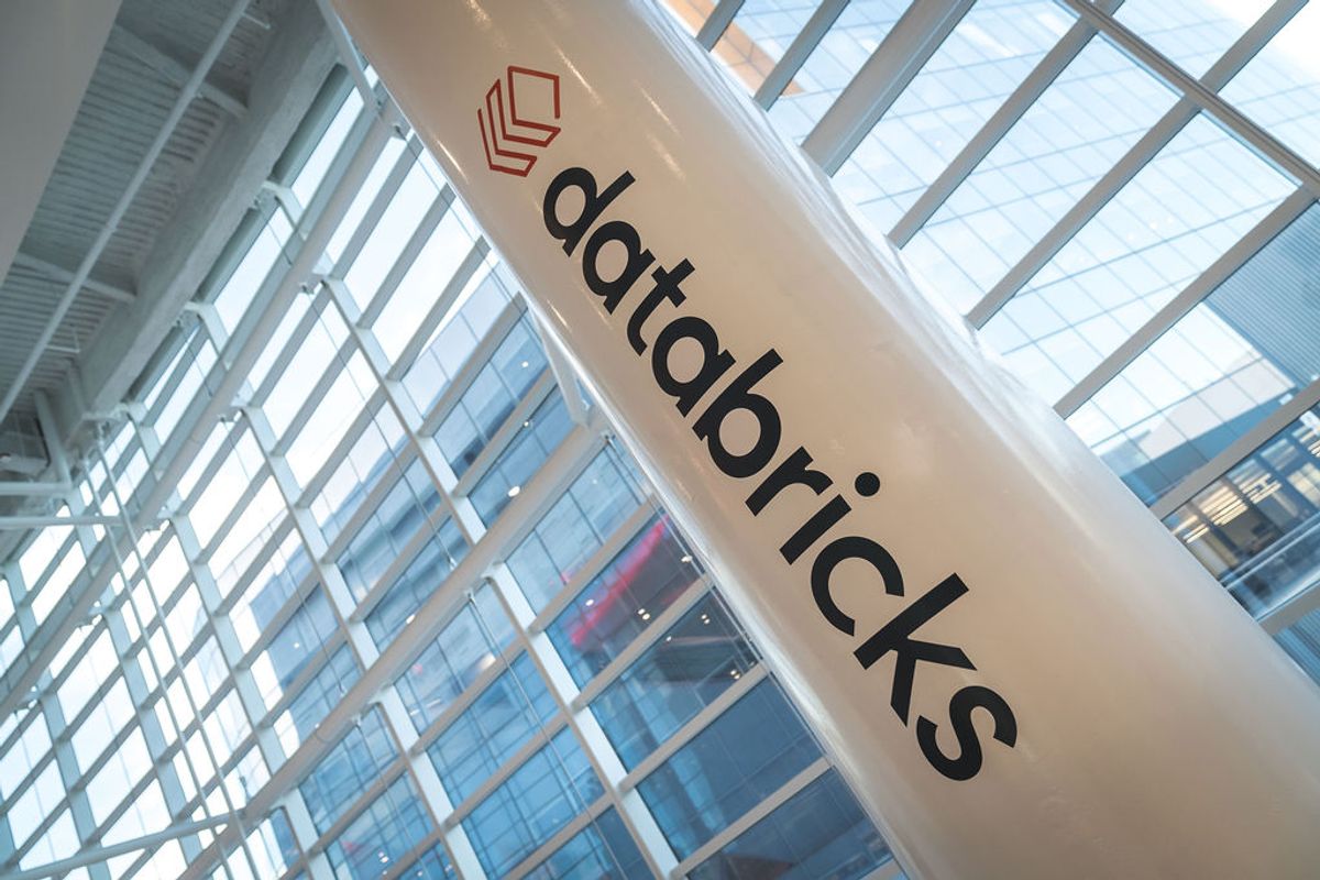 Databricks logo and branding visible on a white pillar inside a modern glass-walled conference venue
