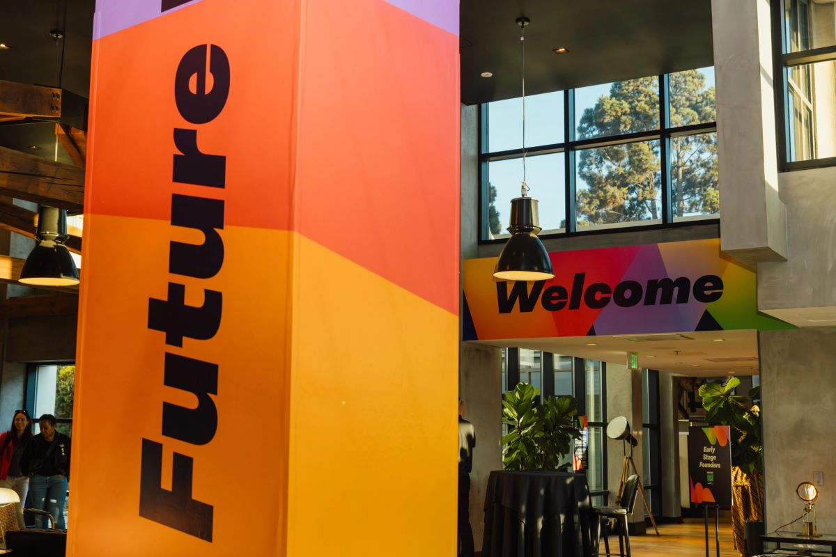 Modern conference space with colorful "Future" and "Welcome" signage, pendant lighting, and industrial windows