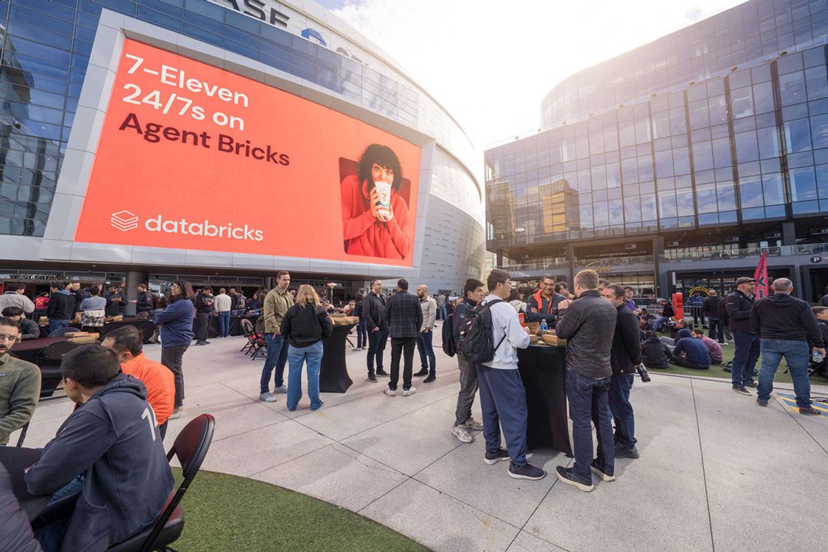 Conference attendees gather in outdoor plaza with large Databricks advertisement display on modern building