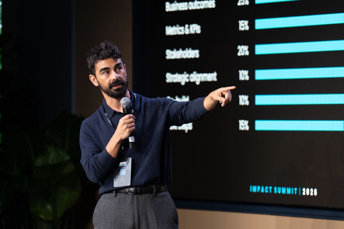 Speaker presenting data on screen showing percentages at Impact Summit 2026 conference
