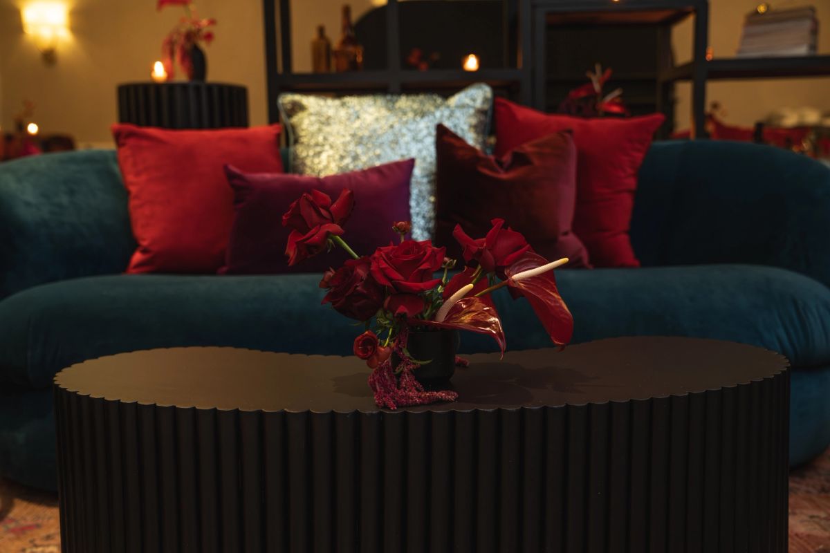 Elegant living room with teal sofa, red velvet pillows, and poinsettia centerpiece on round coffee table