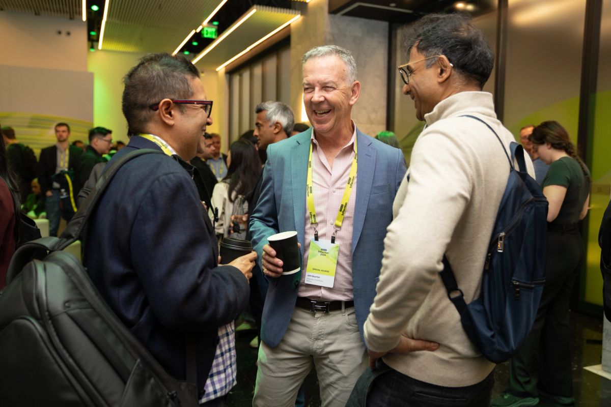 Three attendees networking and laughing at a conference event.