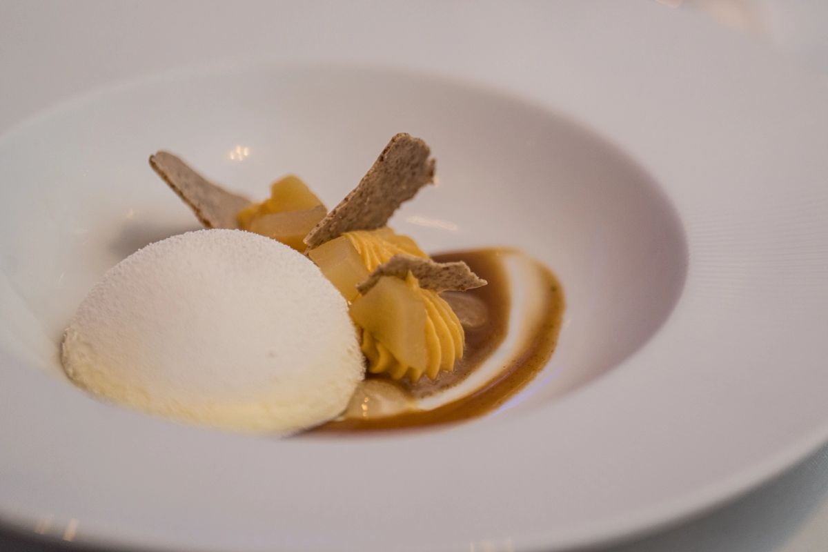Elegant plated dessert with white ice cream scoop, caramel sauce, and decorative garnishes on white plate