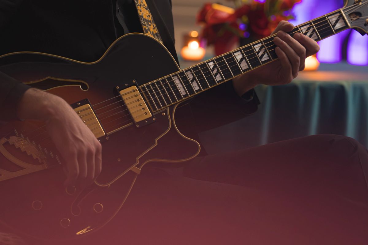 Musician playing electric guitar on stage with colorful stage lighting in background