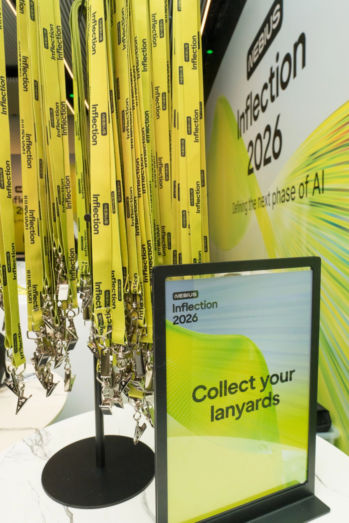 Yellow lanyards displayed at Nebius Inflection 2026 conference station with "Collect your lanyards" sign.