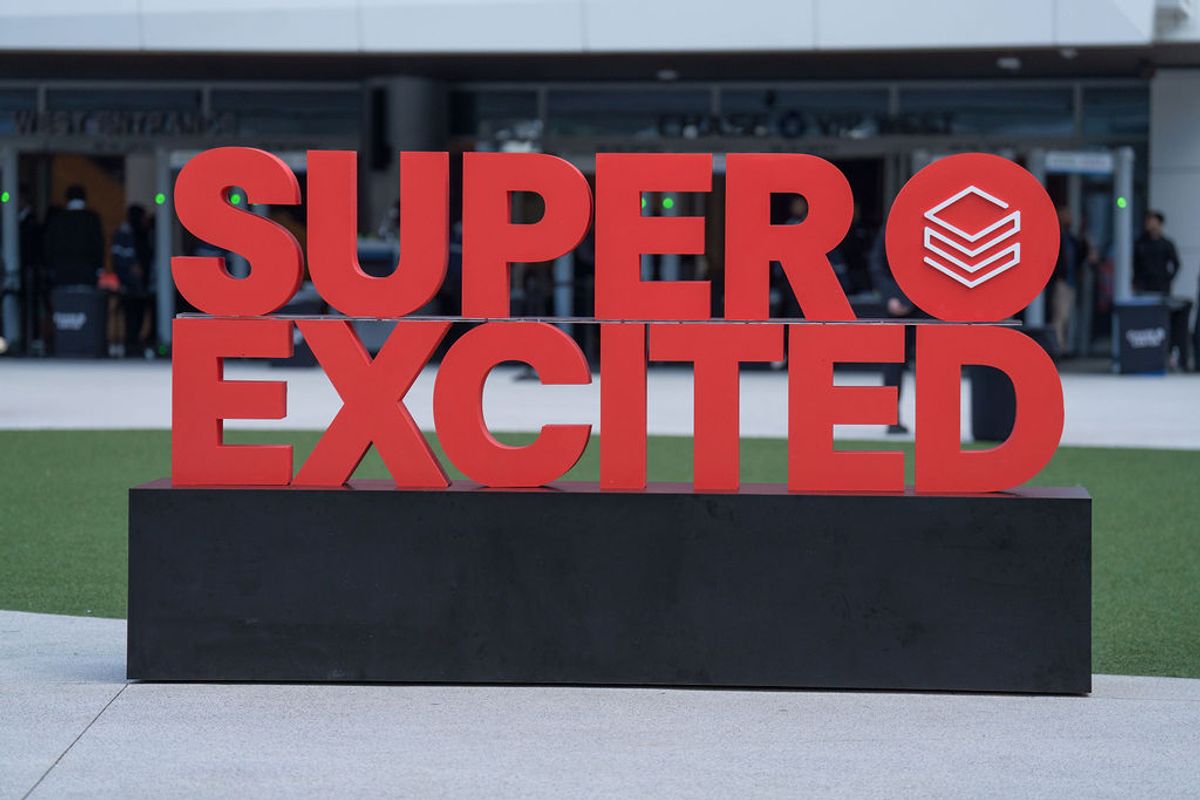Large red "SUPER EXCITED" sign display on black base with modern building in background