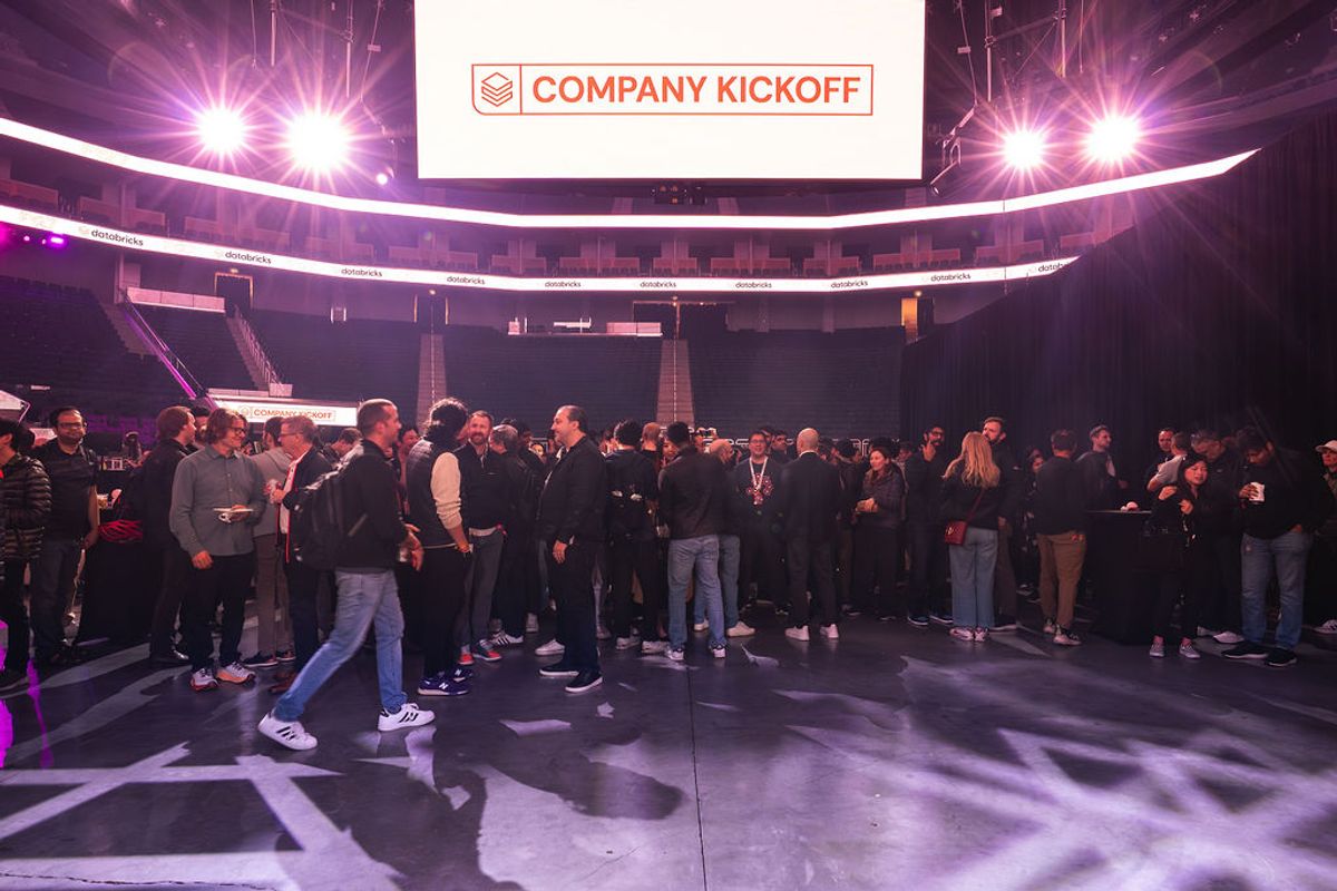 Attendees gather on arena floor under purple lighting with "Company Kickoff" banner displayed overhead