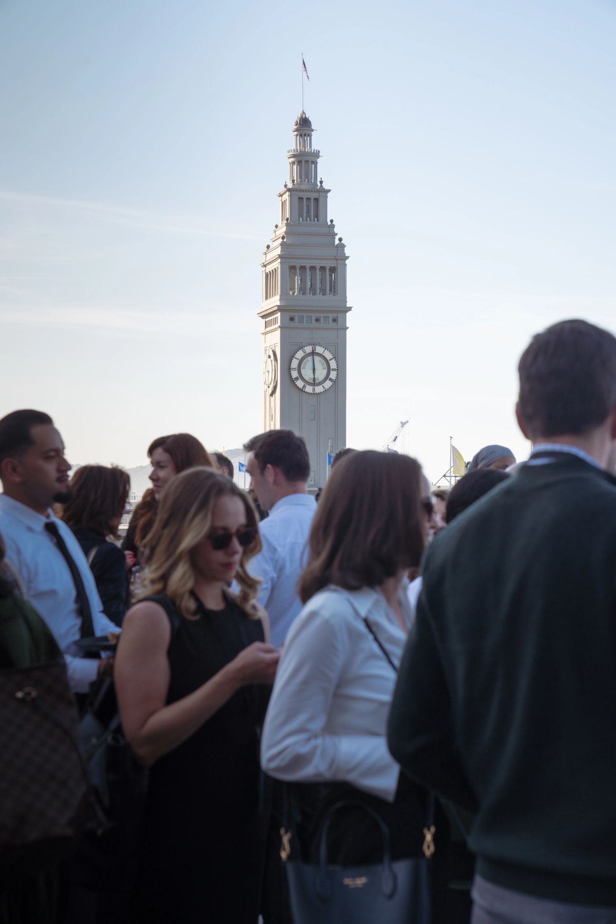 Conference attendees networking outdoors with clock tower in background