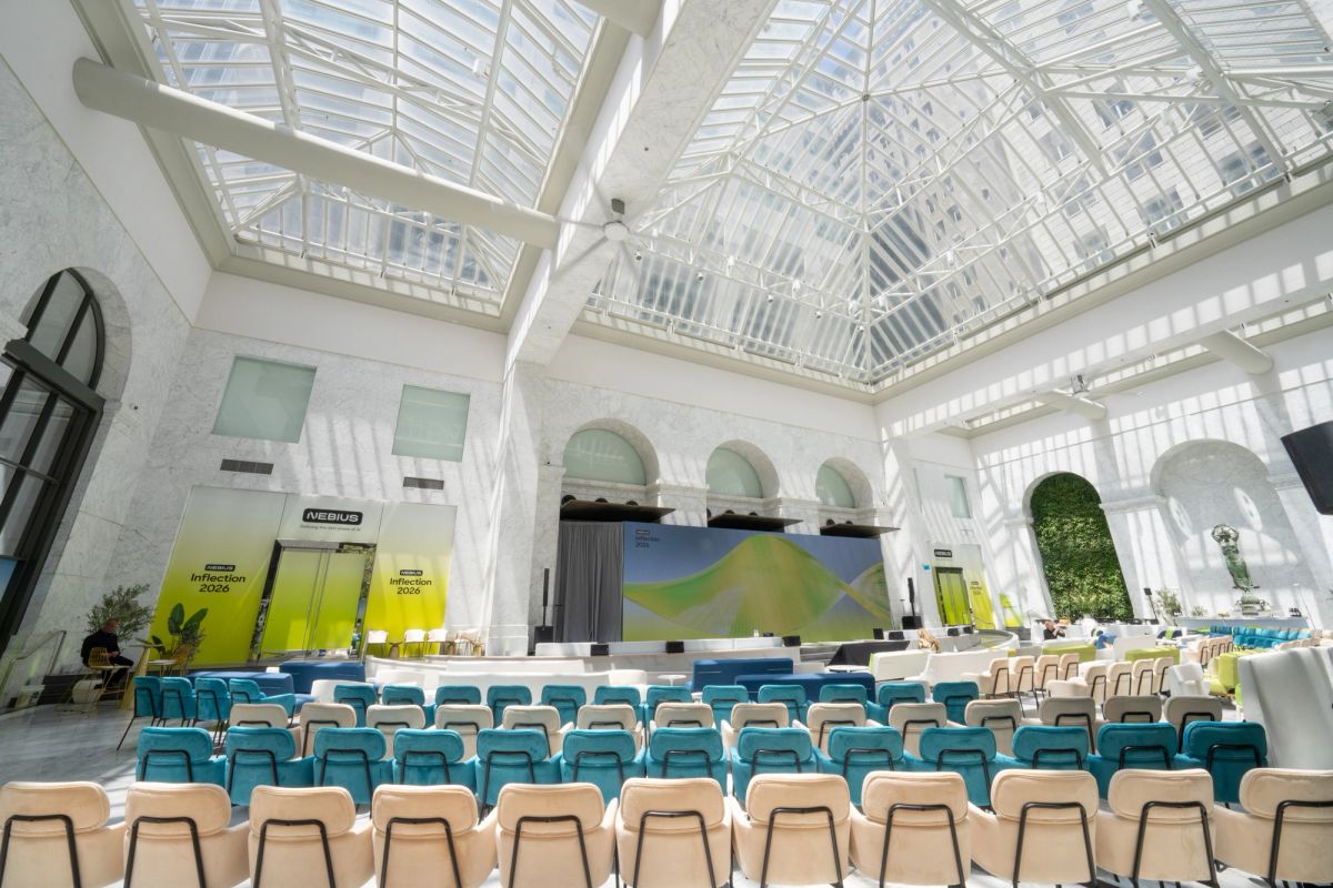 Empty event hall at The Conservatory with teal chairs, stage, and Nebius Inflection 2026 banners.
