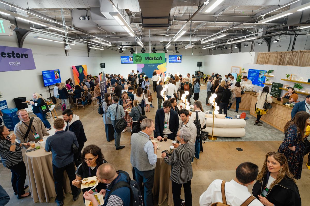 Business professionals networking at indoor conference event with expo booths and branded signage