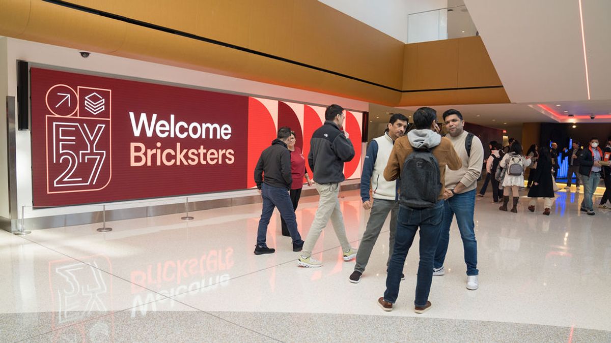 Attendees gather near a red "Welcome Bricksters EY 27" banner in a modern conference venue lobby