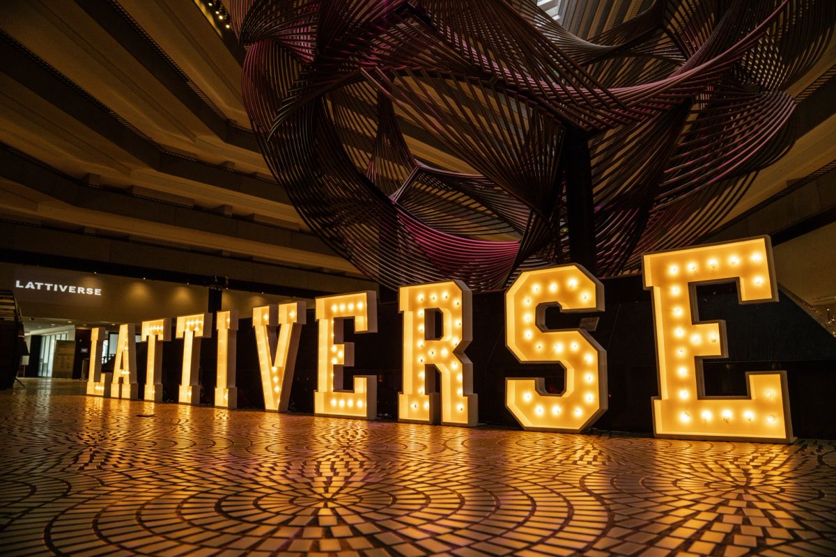 Illuminated marquee letters spelling LATTIVERSE on patterned floor at Hyatt Regency San Francisco.