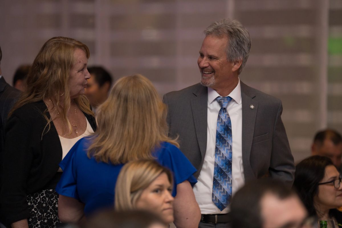 Attendees networking and conversing at an indoor gala event with people seated and standing.