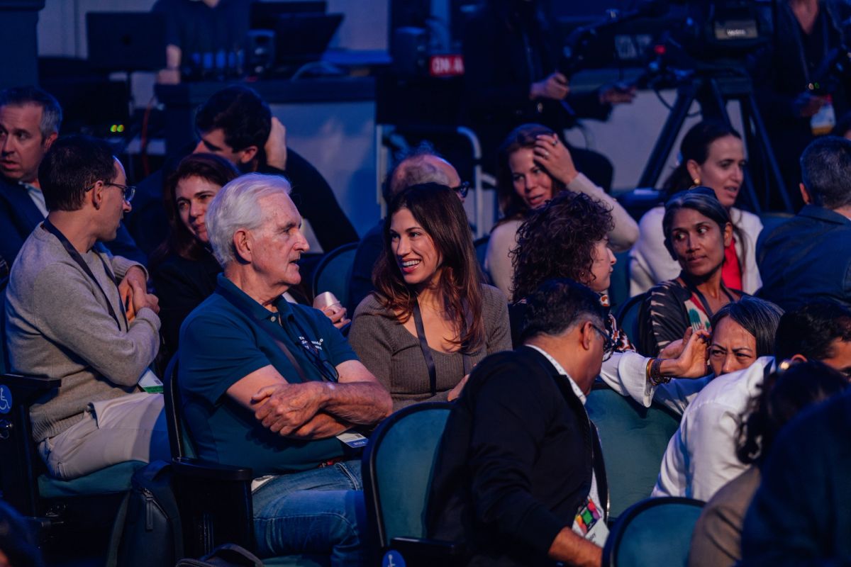 Audience members seated in theater chairs listening during a conference presentation