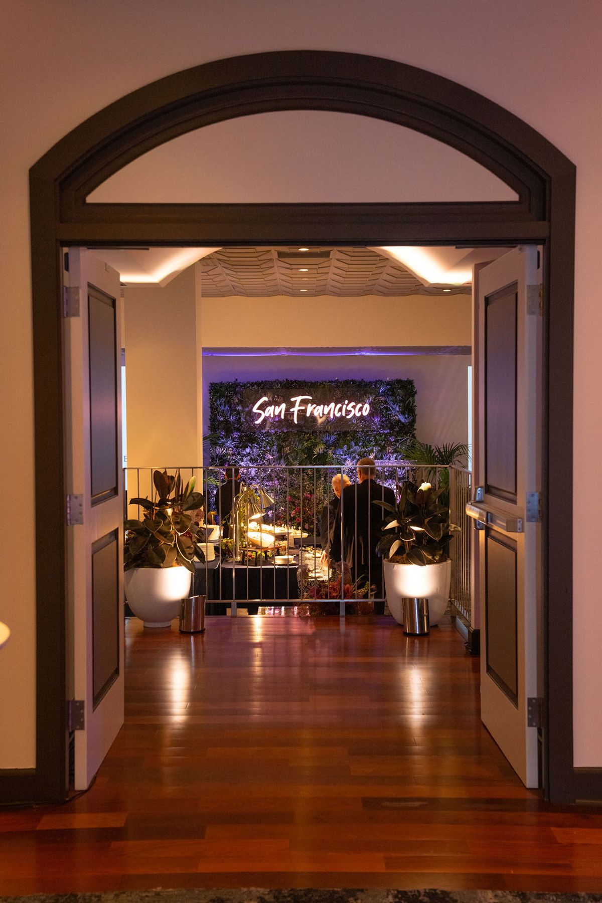 Arched doorway entrance to restaurant with "San Francisco" sign, potted plants, and warm lighting