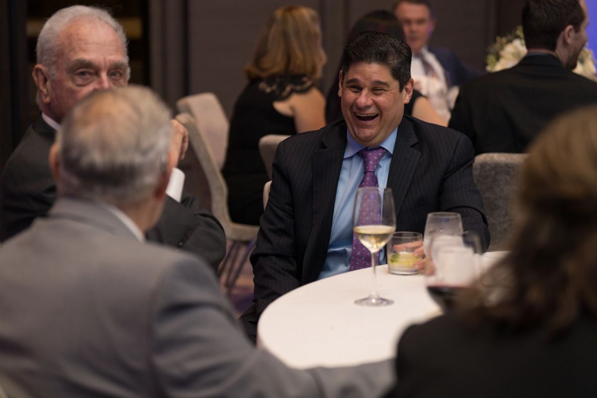 Business professionals in formal attire conversing at round tables during an upscale evening event