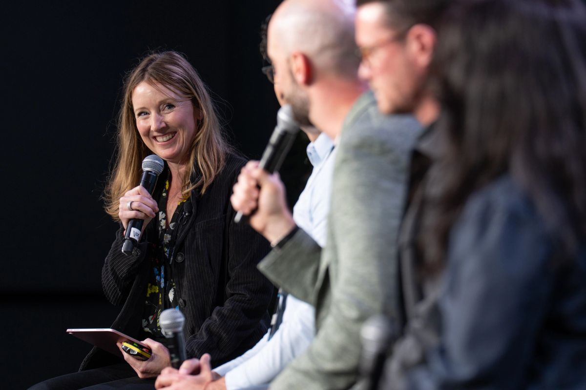 Woman with microphone speaking to bald man during panel discussion at conference event