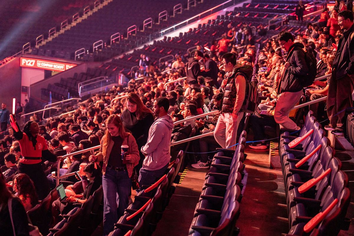Conference attendees filling stadium seating under dramatic red and purple lighting at indoor venue