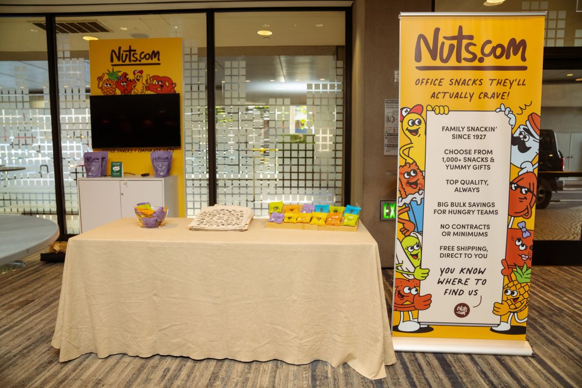 Nuts.com branded booth with snack displays and yellow banner at a conference expo.