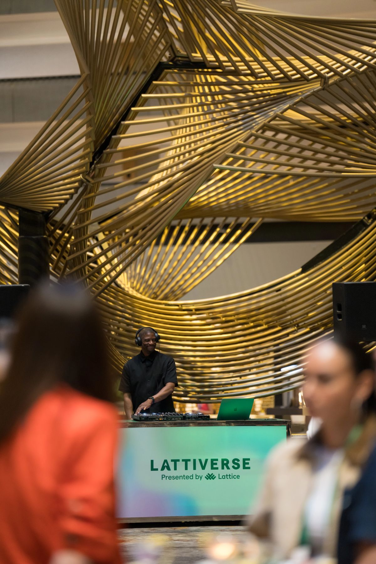 DJ performing at Lattiverse event beneath a golden sculptural installation at Hyatt Regency.