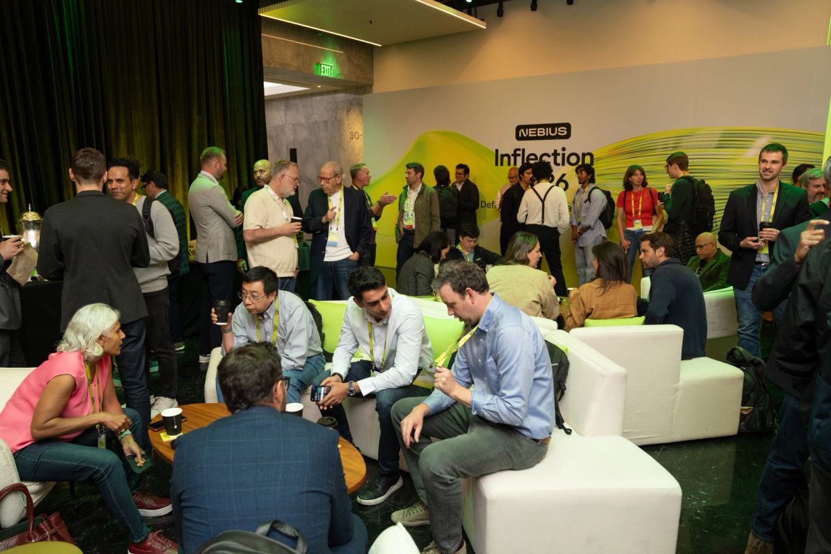 Attendees networking at Nebius Inflection event, seated and standing in groups in a green-lit venue.