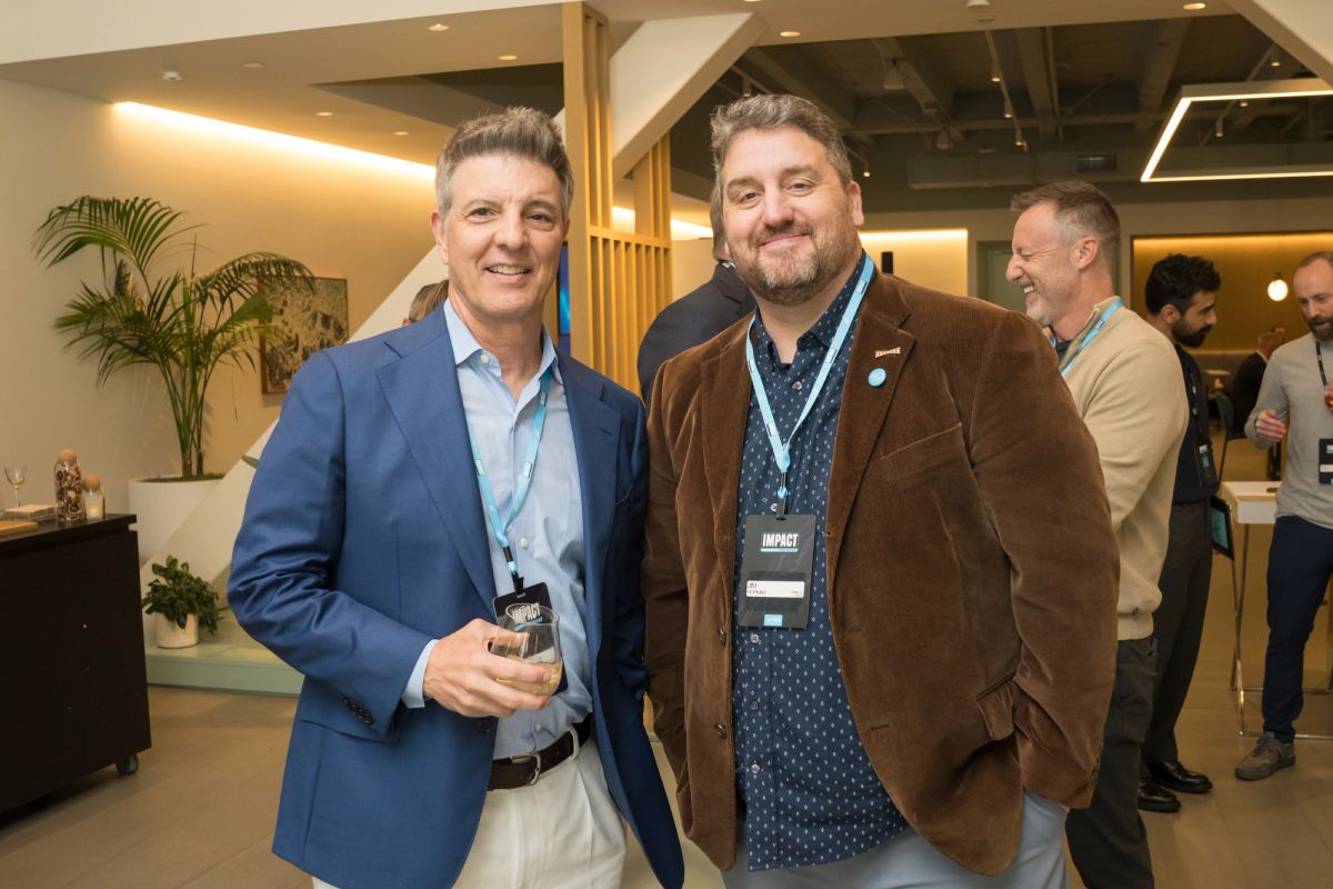 Two men in business attire networking at a conference event in a modern venue with recessed lighting