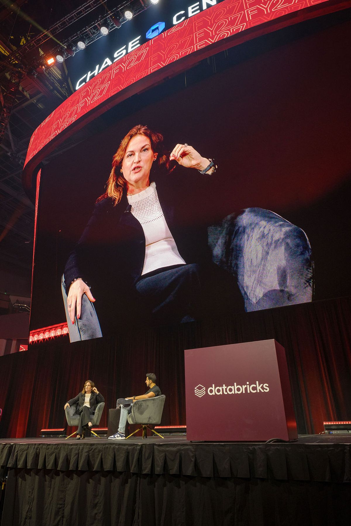 Speaker on stage with large screen behind her at Chase Center conference, Databricks branding visible