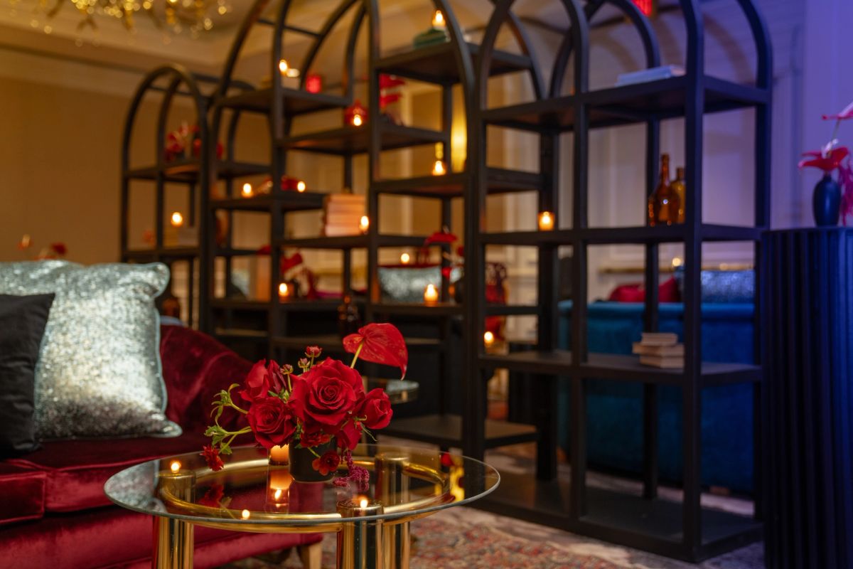 Elegant hotel lounge with red roses on gold coffee table, velvet seating, and illuminated shelving display