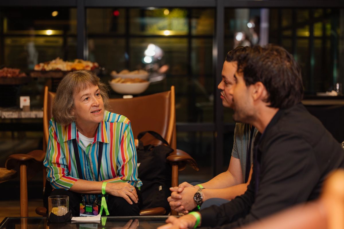 Two people in conversation at a restaurant, woman in colorful striped shirt and man in dark shirt seated at.